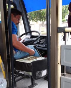 Bus driver with box of coins by Roman Vergara